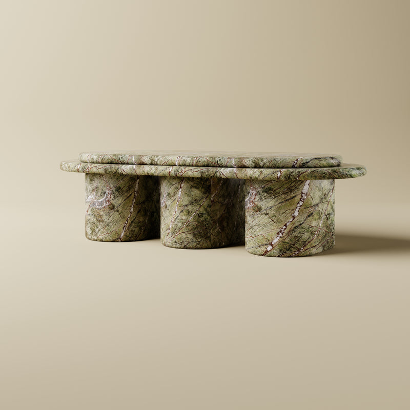 Green marble table with three cylindrical legs on a beige background